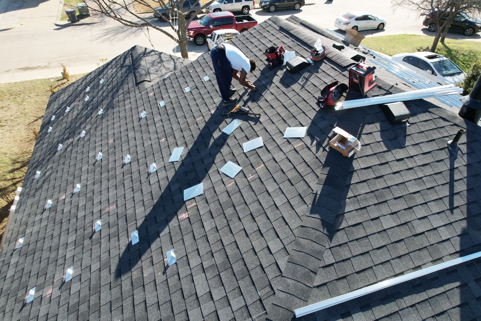 Roofer laying out flashing and shingles across a new dark architectural shingle roof