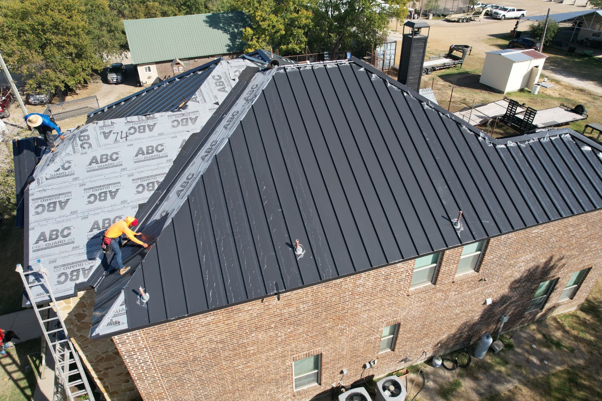 Dallas–Fort Worth brick home at dusk with a new roof, seamless gutters and exterior lighting
